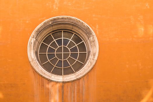 Typical orange color of the facade of a house in Rome. Unusual round window, made of segments.