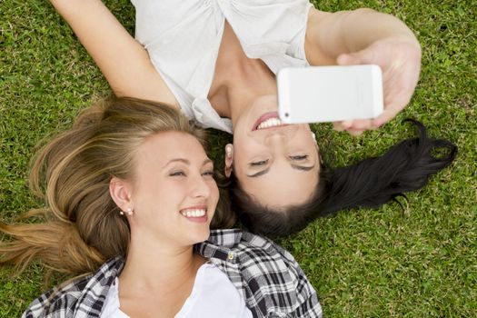 Female best friends lying on the grass and making selfies