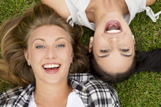 Female best friends lying on the grass and laughing
