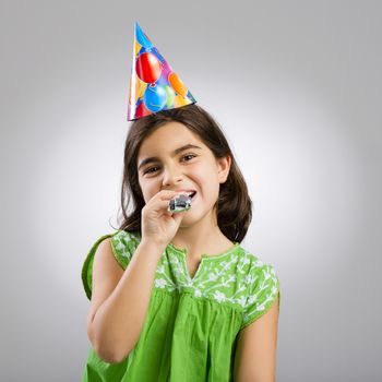 Studio portrait of a little girl wearing a party hat on her birthday