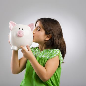 Beautiful and happy young girl holding a piggybank