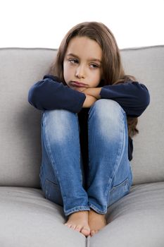 Little girl sitting on a couch and upset with something