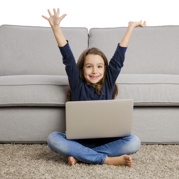 Happy little girl with arms open and working a laptop