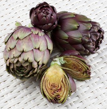 Perfect Raw Artichokes Full Body and Halves closeup on Wicker background