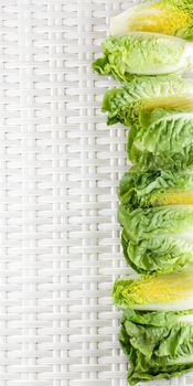 Frame of Fresh Crunchy Romaine Lettuce Full Heads and Halves with Water Drops closeup on Wicker background