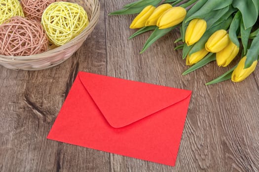 Envelope and yellow tulips on a wooden background