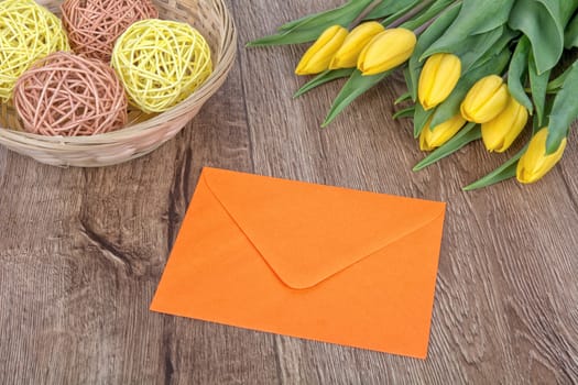 Envelope and yellow tulips on a wooden background
