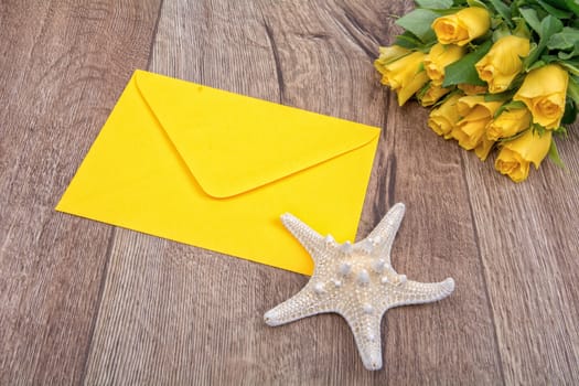 Envelope, white starfish and roses on a wooden background