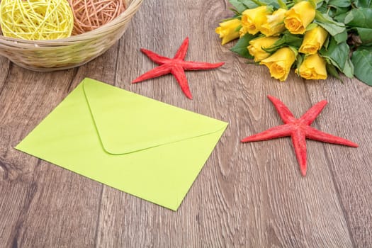 Envelope, white starfish and roses on a wooden background