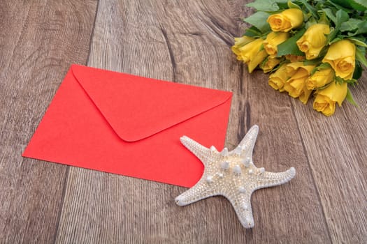 Envelope, white starfish and roses on a wooden background