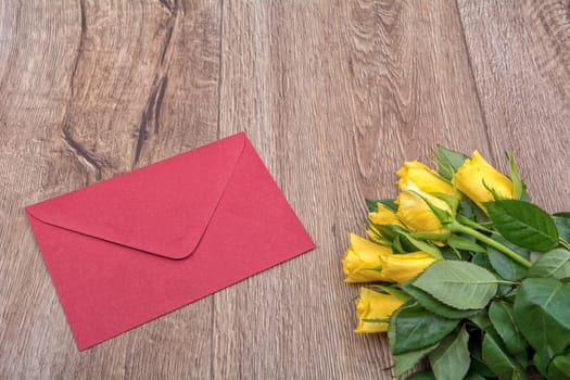 Red envelope and orange roses on a wooden background