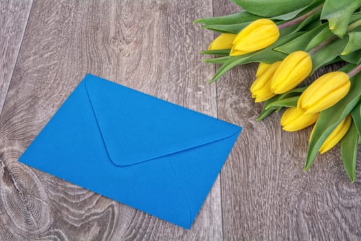 Envelope and yellow tulips on a wooden background