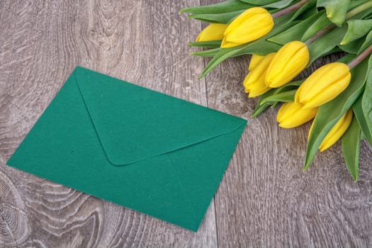 Envelope and yellow tulips on a wooden background