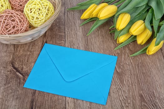 Envelope and yellow tulips on a wooden background