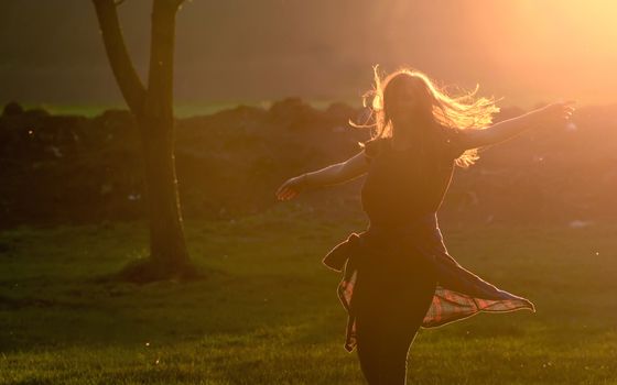 Teen girl jump against beautiful sunset in forest