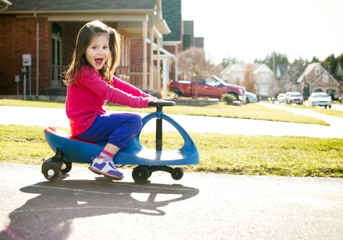 small girl is having fun riding his toy on the street