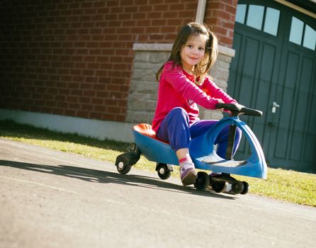 small girl is having fun riding his toy on the street