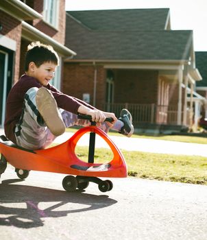 small boy is having fun riding his toy on the street
