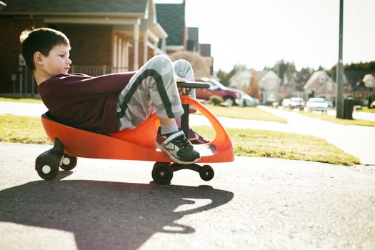 small boy is having fun riding his toy on the street