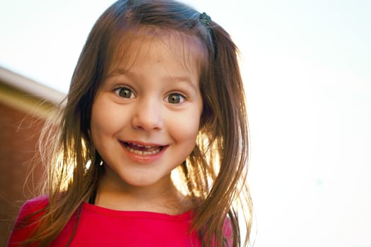 little girl having fun outdoors wearing pink shirt during sunset