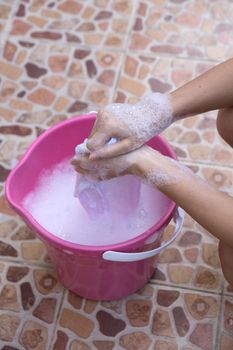 Female Hand washing clothes in the pink basin.