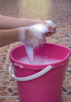 Female Hand Twist clothes in the pink basin.