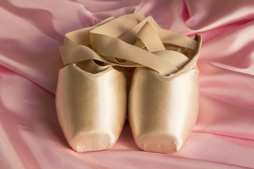 Ballet shoes on delicate pink silk background