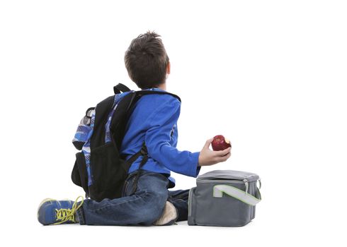 young boy student with backpack and apple in his hand on white background