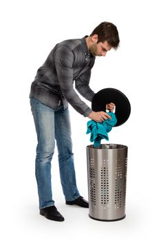 Young man putting a dirty towel in a laundry basket, isolated