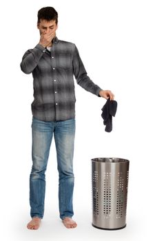 Young man putting dirty socks in a laundry basket, isolated on white