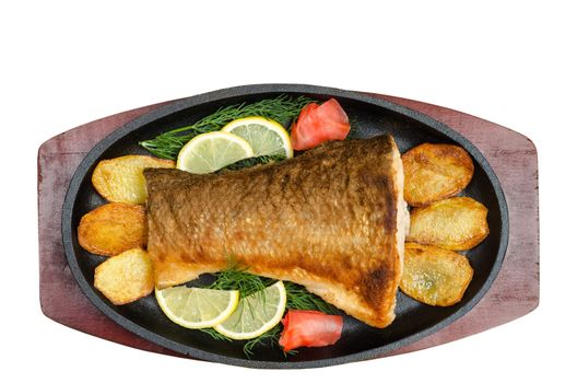 Fried fish with fries,lemon, dill and ginger in a cast iron skillet, is on the Board isolated on a white background.