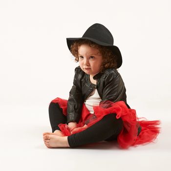 Little girl with black hat sitting and pouting