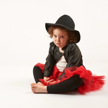 Little girl with black hat sitting and pouting