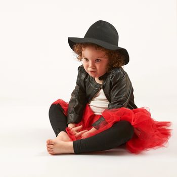 Little girl with black hat sitting and pouting