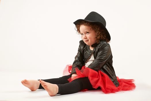 Little girl with black hat sitting and looking up