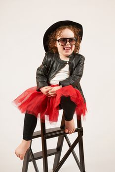 Little girl with black hat sitting on a high stool and dabbles