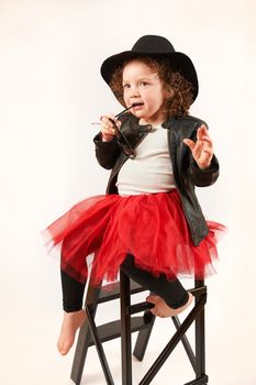 Little girl with black hat and sunglasses sitting and thinking
