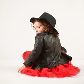 Little girl with black hat sitting and turned