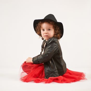 Little girl with black hat sitting and looks