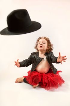 Little girl sitting and trying to catch his hat