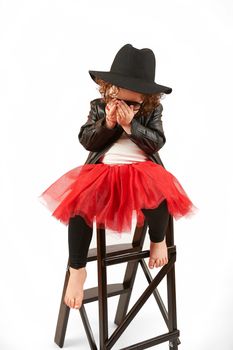 Little girl with black hat sitting on a high stool and shy