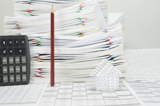 House on finance account have blur pencil and calculator place vertical and overload of paperwork with colorful paperclip as background.