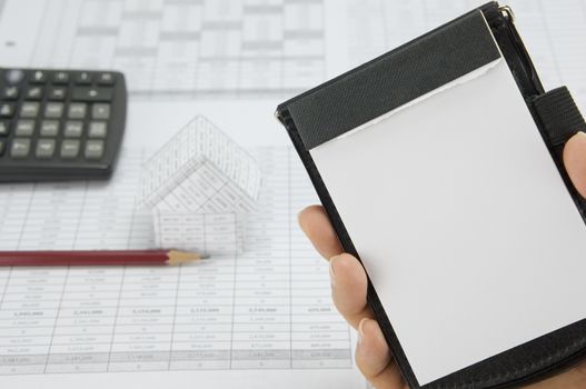 Man holding notepad have blur pencil and house with calculator on finance account as background.