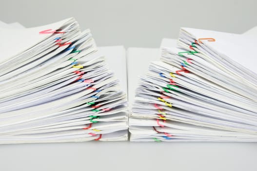 Step pile overload document of receipt and report with colorful paperclip on white table.