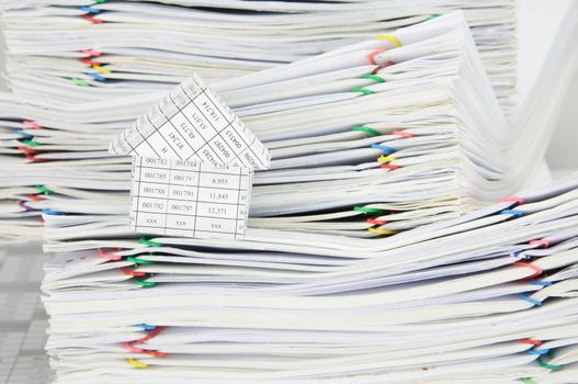 House and overload of paperwork with colorful paperclip on finance account.