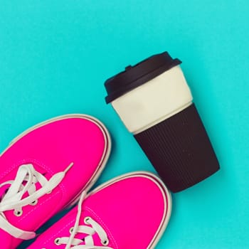 Pink sneakers and a cup on a blue background