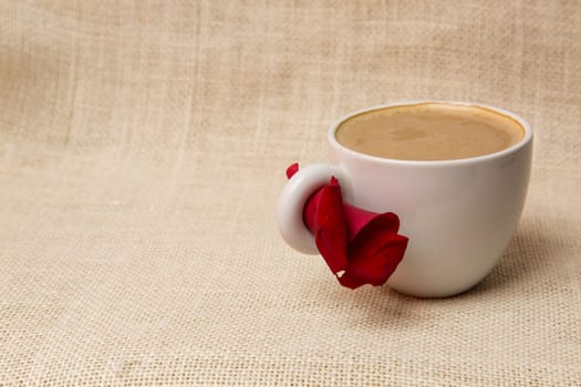 Cup of coffee with a rose petal in a lovely morning