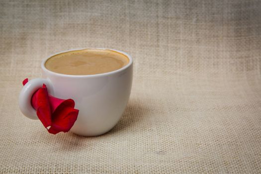 Cup of coffee with a rose petal in a lovely morning