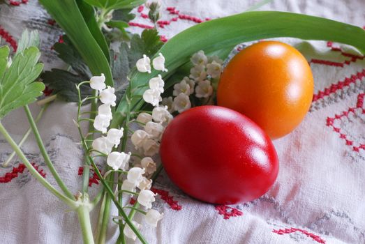 shining red and orange Easter eggs with lily of the valley plant