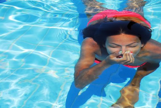 teenage girl diving in the blue transparent swimming pool underwater holding breath